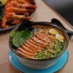 Savory ramen bowl with sliced meat, herbs, and eggs, garnished for authentic Asian flavor.